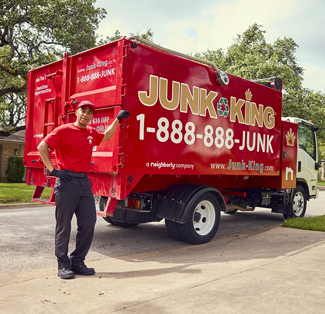 Junk King professional standing beside a red branded dump truck.
