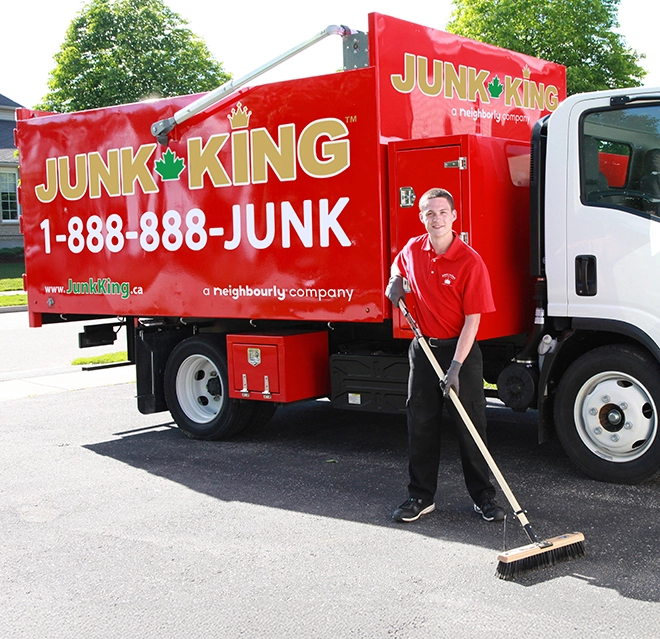 Junk King professional standing beside a red branded dump truck.